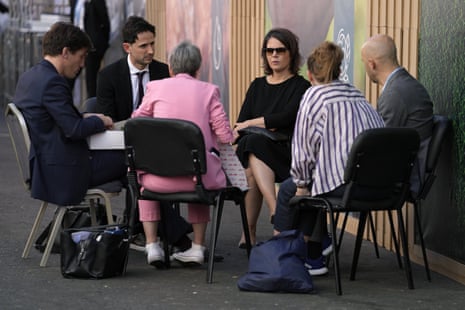 Germany’s foreign minister, Annalena Baerbock (wearing sunglasses), sits in a huddle outside the centre.