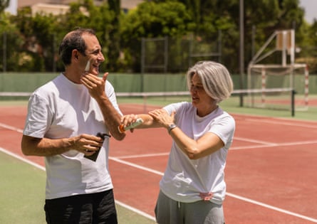 Two people applying sunscreen at a tennis court