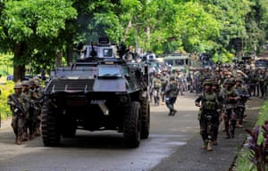 An armoured personnel carrier and government troops are seen marching towards Marawi