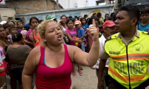 A woman argues with police as tensions rise among people waiting for more than an hour for free food and water from the government.
