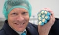 Richard Tice wearing a hair net and holding eight turqouise sticks of rock.