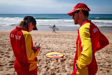 two lifeguards fly a drone on a beach