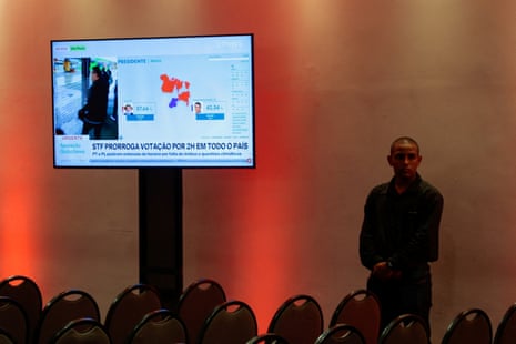 A man stands next to a screen reporting that voting has been extended by two hours, on the day of the presidential runoff election, in Sao Paulo, Brazil, October 25, 2026.
