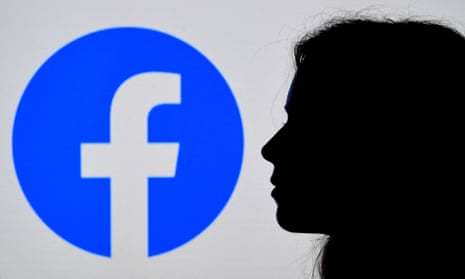 A person looks a Facebook App logo displayed on the background