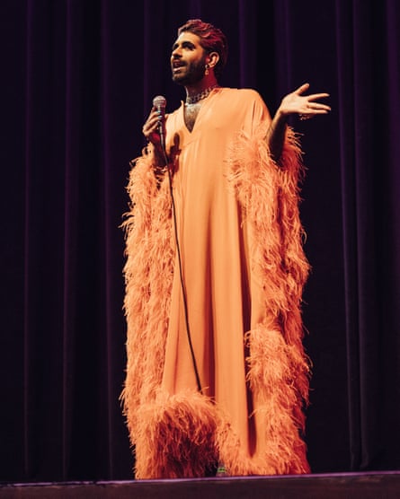 Alok Vaid-Menon, the American gender-nonconforming artist and speaker, in an orange robe speaking on stage