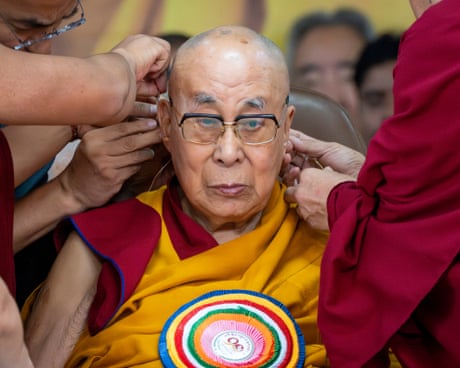 Monks attach a microphone to the Dalai Lama