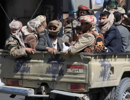 Men wearing headscarves and carrying rifles in the back of a pickup truck