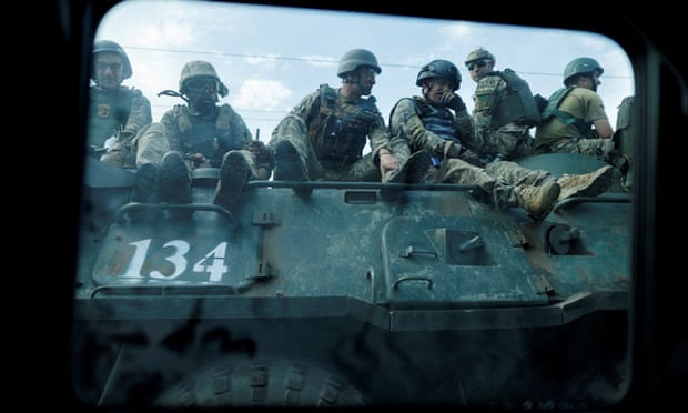 A group of soldiers sitting on an armoured vehicle