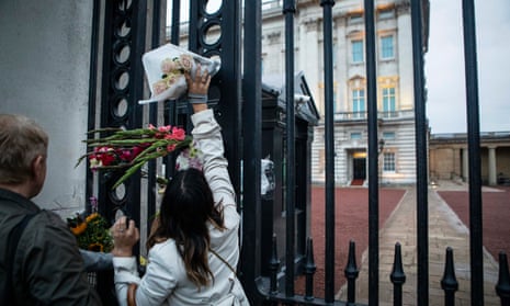 People putting flowers on the gates of Buckingham Palace after the announcement of the death of Queen Elizabeth.