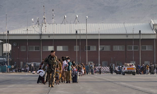 A US air force airman guides evacuees to board a plane at Hamid Karzai international airport in Kabul on Tuesday.