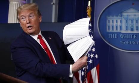 Former US President Donald Trump holds up papers in the James Brady Press Briefing Room of the White House on April 20, 2020.