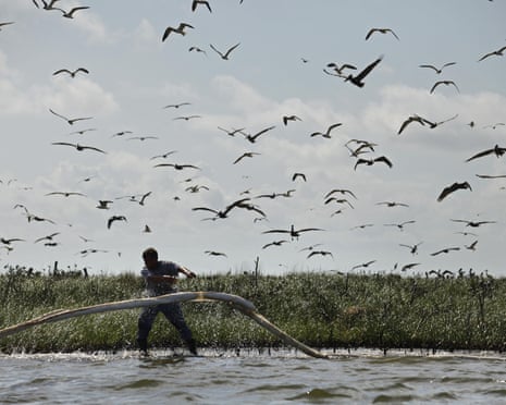 FILE - In this May 22, 2010 file photo, a man lays oil absorbent boom as oil from the Deepwater Horizon oil spill impacts Cat Island in Barataria Bay, in Plaquemines Parish, La. Ten years after an oil rig explosion killed 11 workers and unleashed an environmental nightmare in the Gulf of Mexico, companies are drilling into deeper and deeper waters where the payoffs can be huge but the risks are greater than ever. (AP Photo/Gerald Herbert, File)