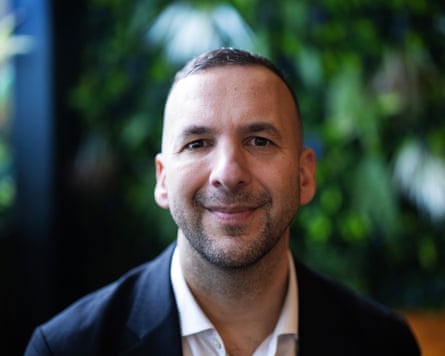 Polanski looks into the camera and smiles. He is wearing a shirt and jacket