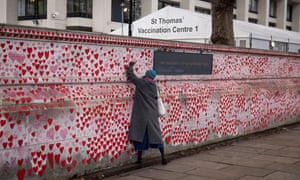 A member of the public writes on a wall of remembrance for Covid-19 victims near St Thomas' hospital