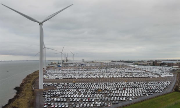 New cars in a compound next to wind turbines in Sheerness, Kent.