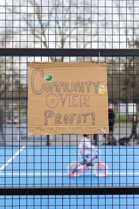 A sign on the fence at Bethnal Green Gardens Padel court says ‘Community over profit’ and a child rides a bike on the court