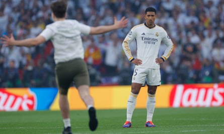 Jude Bellingham looks on as a pitch invader stops play early in the Champions League final.