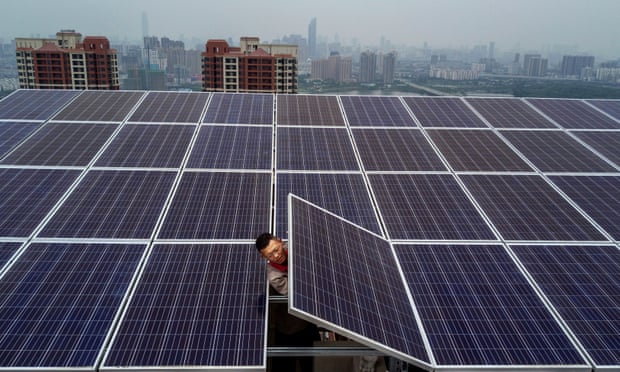 A man adjusts a solar panel on the roof of a 47-storey building in Wuhan, China.