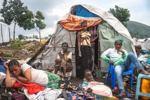 A family sits outside a tent