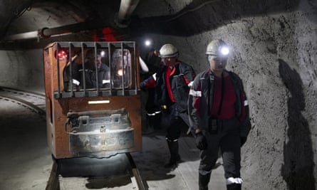 A woman walks with male colleagues underground in a coal mine.