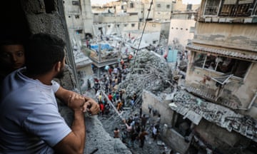 Palestinians watch rescue efforts from their homes as civil defense teams and residents carry out search and rescue efforts after an Israeli attack hits a house belonging to the Al Nadi Family in the al-Daraj neighbourhood of Gaza City on Friday.