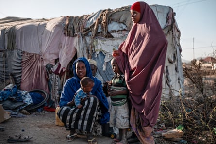 A family gather outside a makeshift shelter in a camp for displaced people