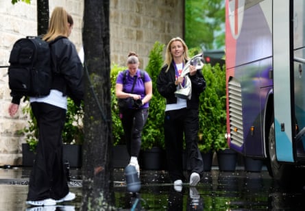 Leah Williamson carries a trophy while walking towards a coach