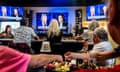 people eat and drink at a restaurant while watching the debate on TV