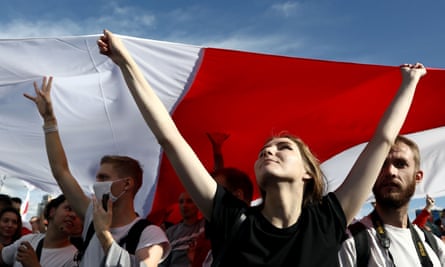 Opposition supporters carry a huge flag of the pre-Soviet republic of Belarus