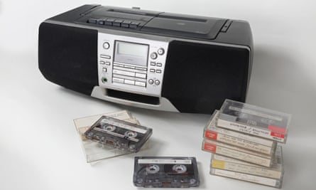 Home recorded cassette tapes stacked up in front of a 1990s style cassette, radio and and CD player.