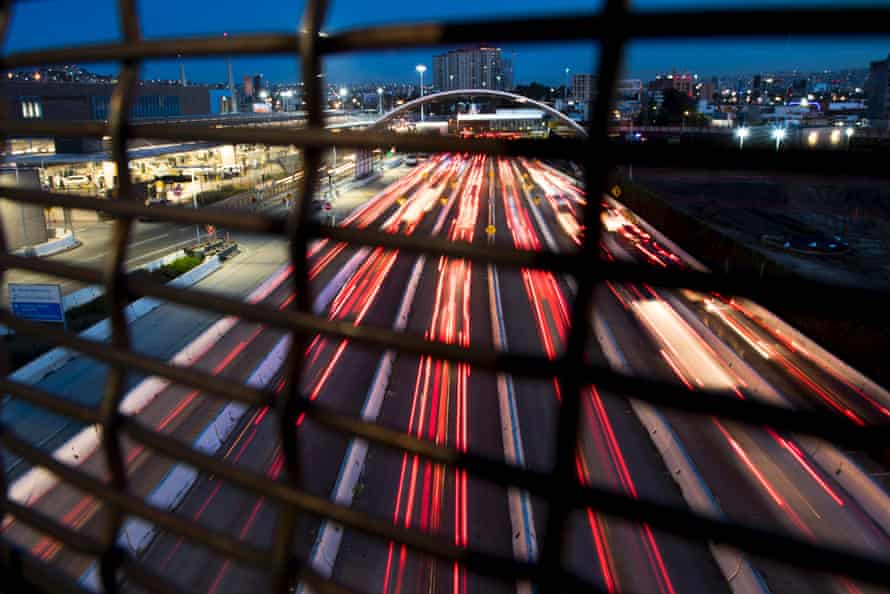 A stream of tail lights illuminate the road as cars cross the border into Mexico from San Diego