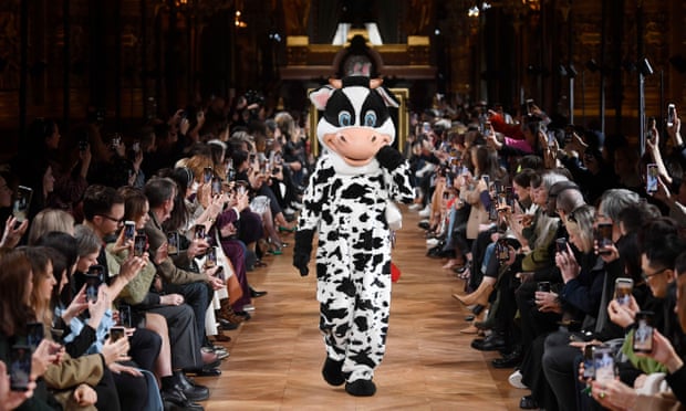 Person in a cow costume models a bag at the Stella McCartney show in Paris