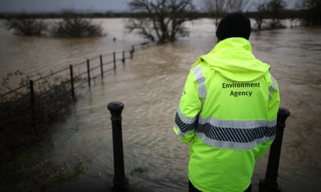 An Environment Agency employee looks at flood water from the river Arun, January 2014, in Pulborough, England.