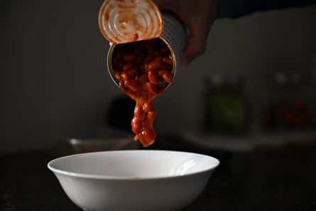 Luscious red baked beans being poured from a tin into a white bowl