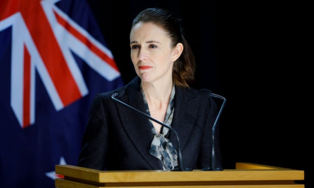 Jacinda Ardern at a lectern with the New Zealand flag behind her