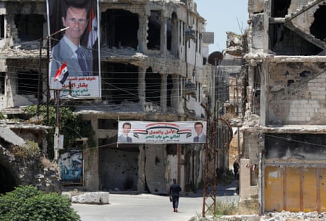 Banners of Bashar al-Assad hang from ruined buildings