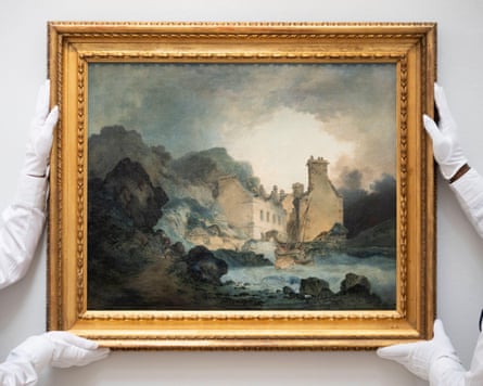 Two people in white gloves hold up a Turner painting of craggy rocks, sea and a building in a gilt frame