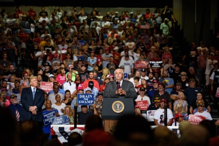 a man in a suit at a podium in front of a crowd of people