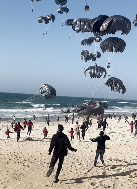 People running toward falling food parcels dropped from US aircraft on to a beach in Gaza on 2 March.