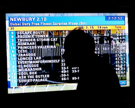A man watches Racing UK coverage of Newbury races at a betting shop.