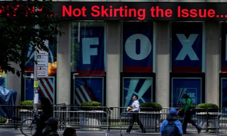 People pass by ads for Fox News on the News Corporation building in Manhattan.