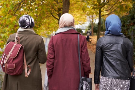 Three Muslim women walking on an autumn day, backs to camera