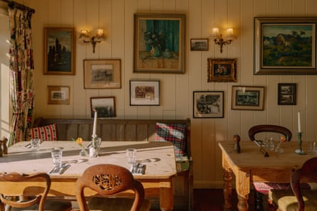 Tables in a pub set for meals, with lots of paintings on the wood-panelled wall behind