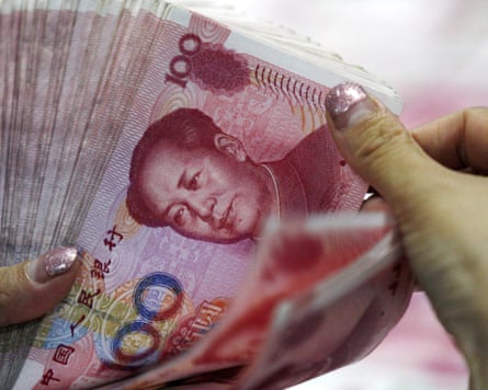 A bank clerk counts Chinese currency notes at a bank outlet in Huaibei in central China’s Anhui province