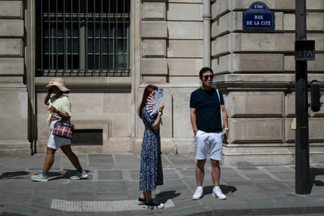 A woman uses a handfan at a pedestrian street crossing in central Paris, as France experiences a heat wave