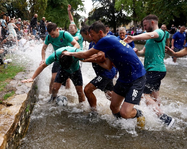 Players kick a ball in a shallow river