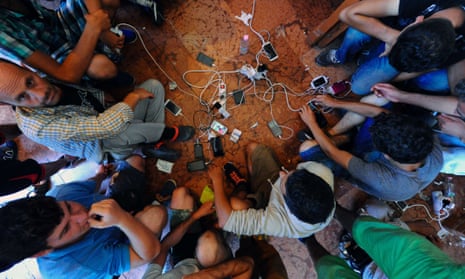 Migrants charge their mobile phones.