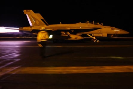 Flames shoot out from the back of a fighter jet as it takes off at night