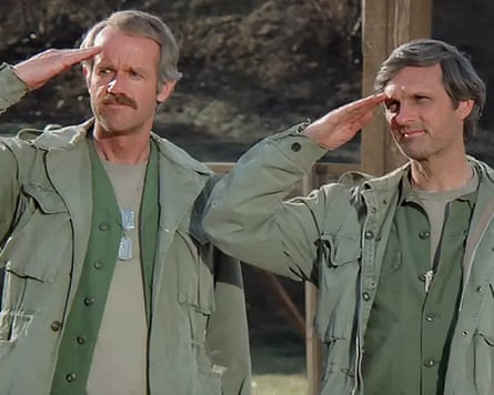 Two characters from M*A*S*H, Hawkeye and BJ are saluting and looking to the side.