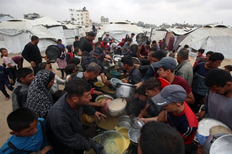 Palestinians wait in long queues to receive pots of food distributed by charitable organizations, in Gaza city on Tuesday.